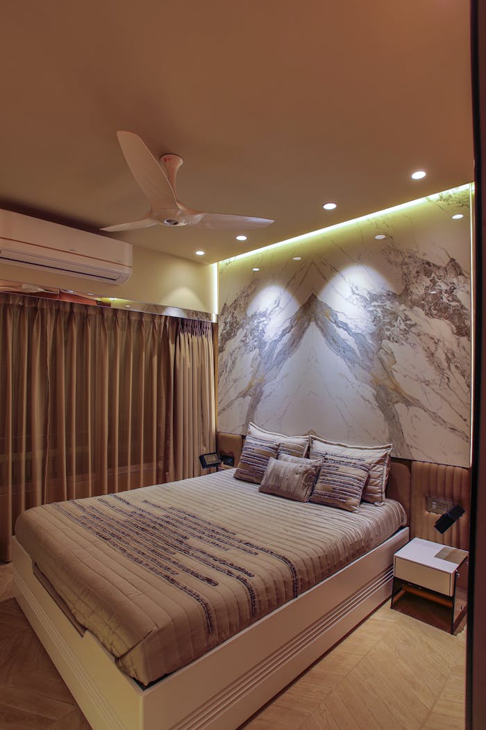 services-01 Stylish bedroom with ambient lighting and contemporary decor features a ceiling fan and artistic wall design.
