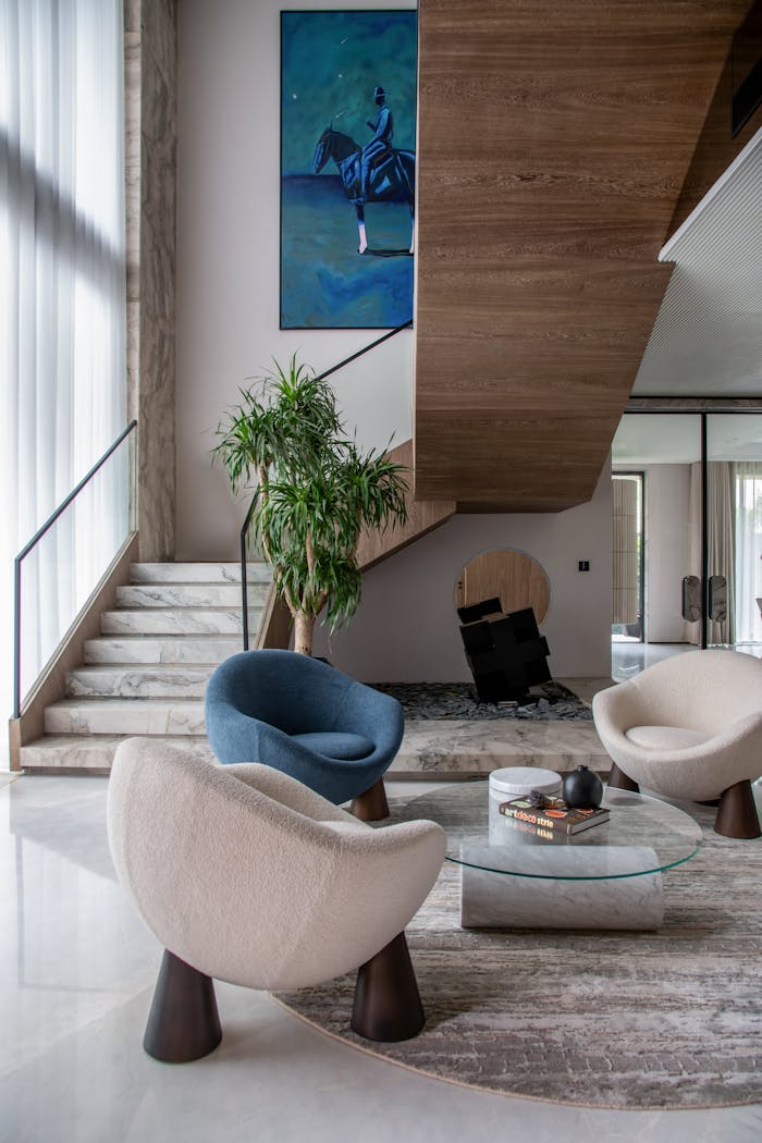 services-01 Elegant modern living room featuring unique chairs, art, and staircase for luxury appeal.