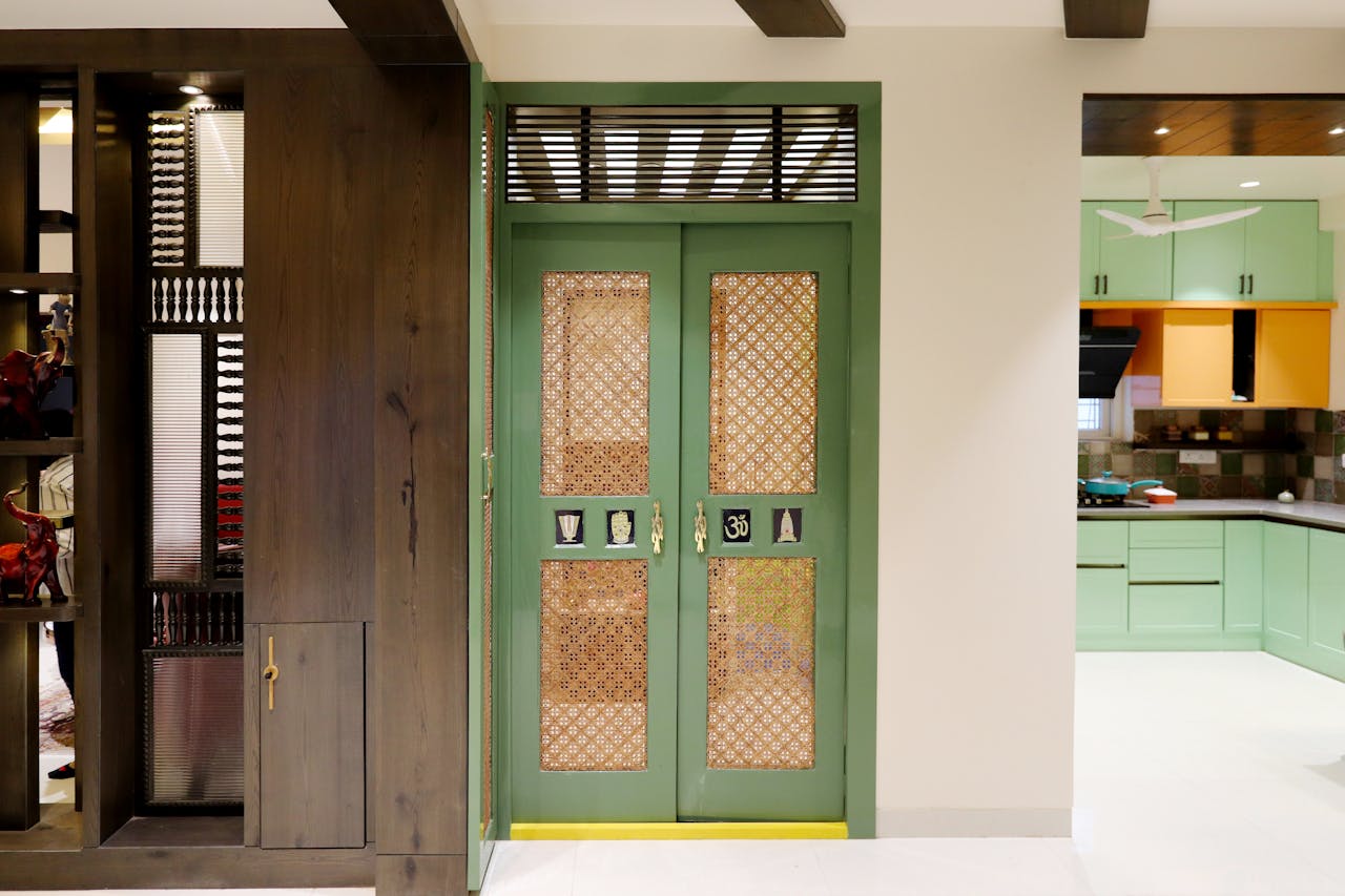 why-choose-us Stylish green doorway featuring intricate lattice designs, leading to a brightly lit modern kitchen.